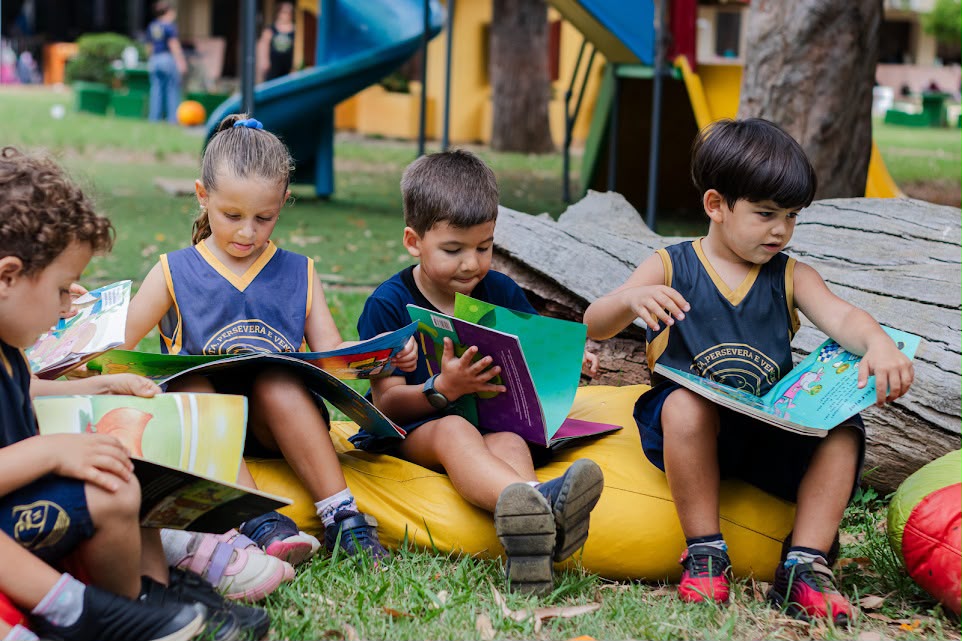 Crianças da Educação Infantil lendo livros em área externa
