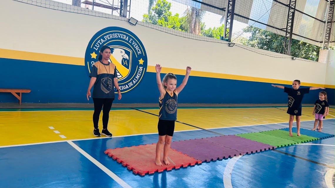Crianças da Educação Infantil realizando atividade de ginástica artística em quadra