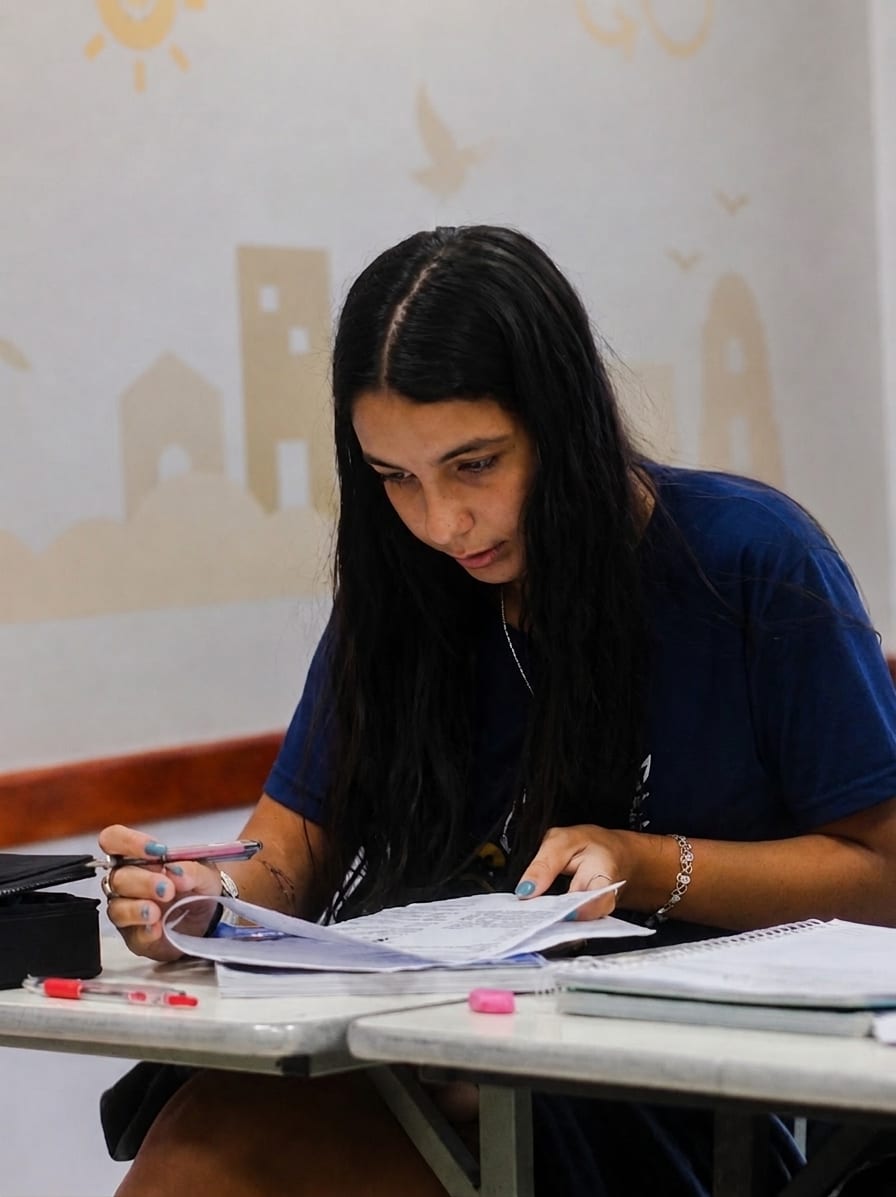Aluna do Ensino Médio concentrada na leitura de uma atividade em sala de aula