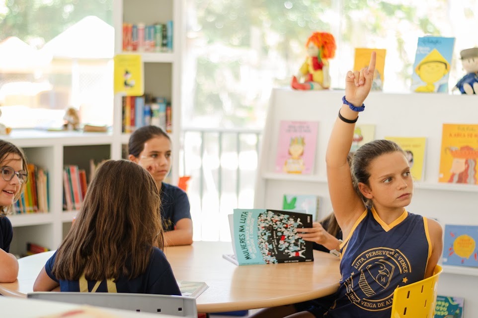 Aluna dos Anos Iniciais participando de roda de leitura na biblioteca
