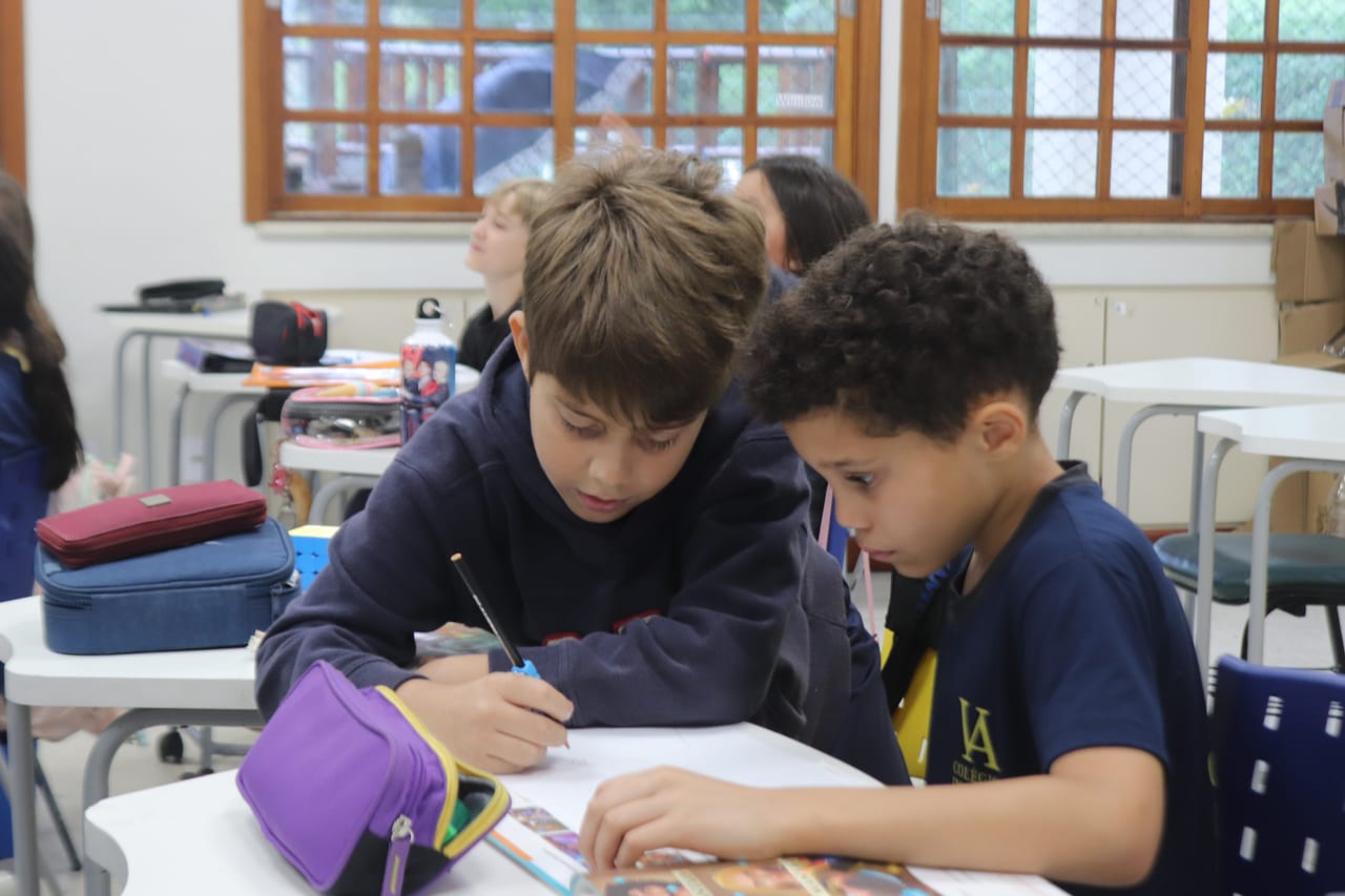Dois alunos dos Anos Iniciais resolvendo juntos uma atividade de Inglês em sala de aula